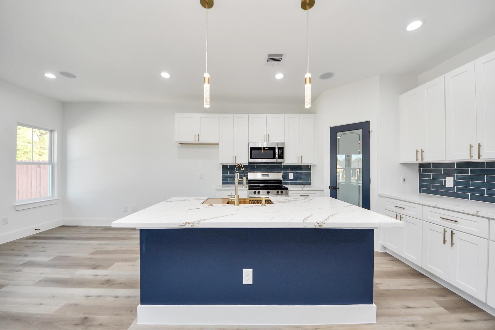 4606 Mallow Street, Unit B Houston, TX 77051 - Photo 12 of 25 a room with kitchen island a sink wooden floor and white appliances