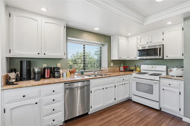 a kitchen with white cabinets white stainless steel appliances and sink