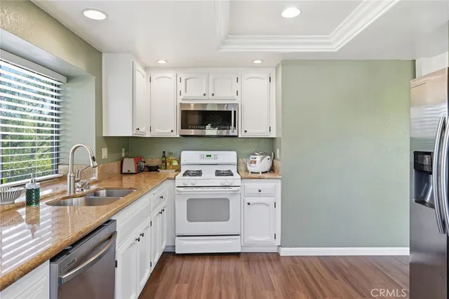 a kitchen with a sink cabinets stainless steel appliances and a window