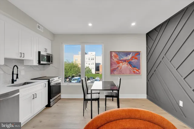 a open kitchen with stainless steel appliances granite countertop a stove top oven a sink dishwasher and white cabinets with wooden floor