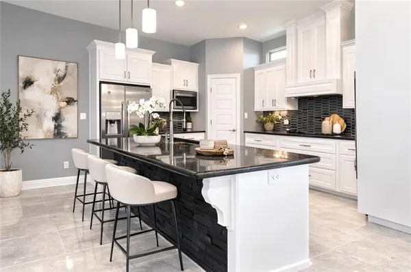 a kitchen with stainless steel appliances kitchen island granite countertop a sink a stove a dining table and chairs