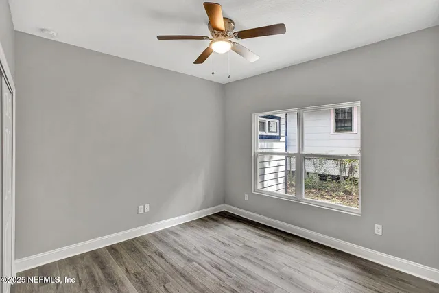 a view of an empty room with window and wooden floor