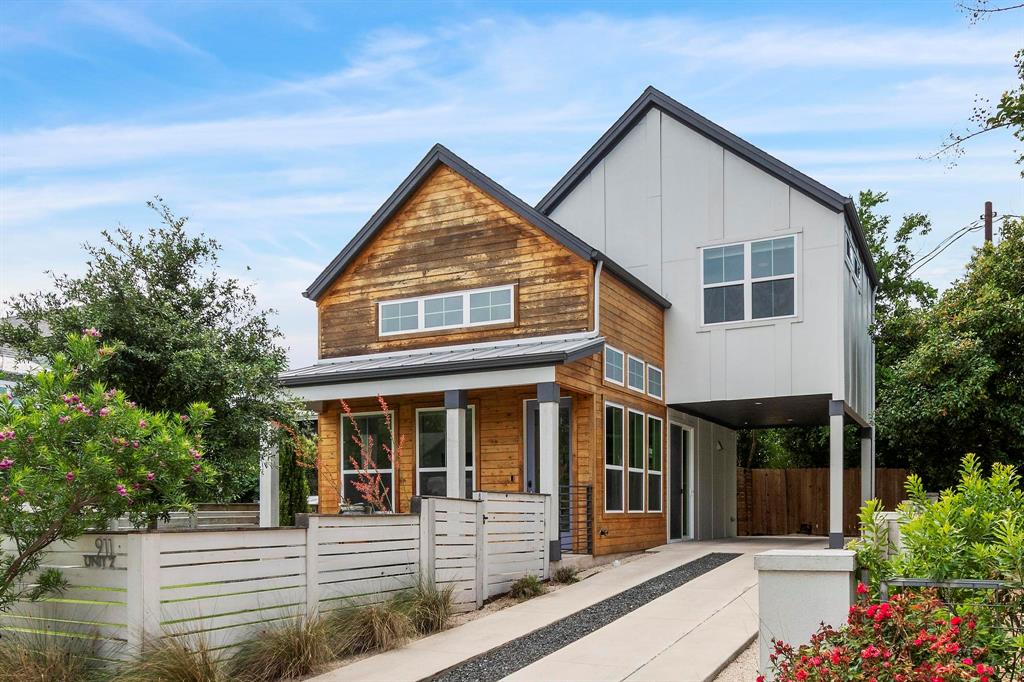 911 Stobaugh Street, Unit 2 Austin, TX 78757 - Photo 1 of 26 Modern exterior featuring a combination of wood siding and vertical white siding, a covered porch with dark columns, multiple large windows, a covered carport area, and a white horizontal slat fence