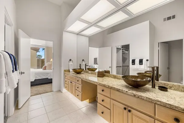 a spacious en suite bathroom with a granite countertop double vanity