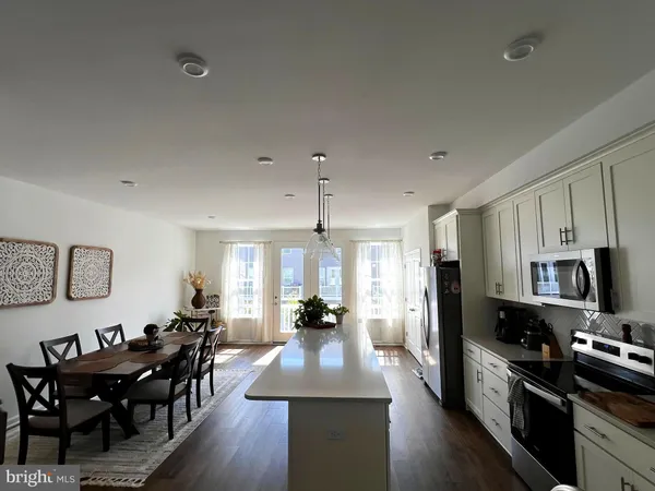 a large kitchen with sink a refrigerator a stove a dining table and chairs