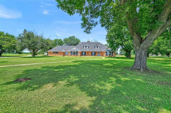 a view of a big house with a big yard and large trees