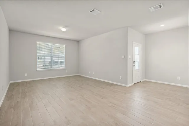 a view of an empty room with wooden floor and a window