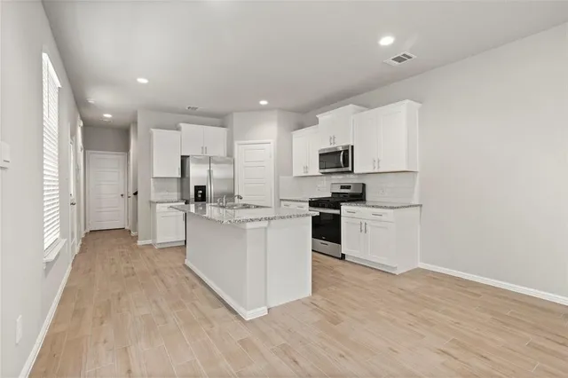 a kitchen with white cabinets and stainless steel appliances