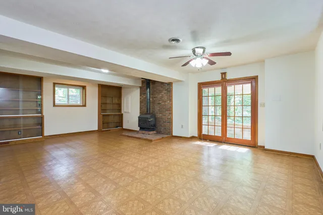 an empty room with wooden floor ceiling fan and windows