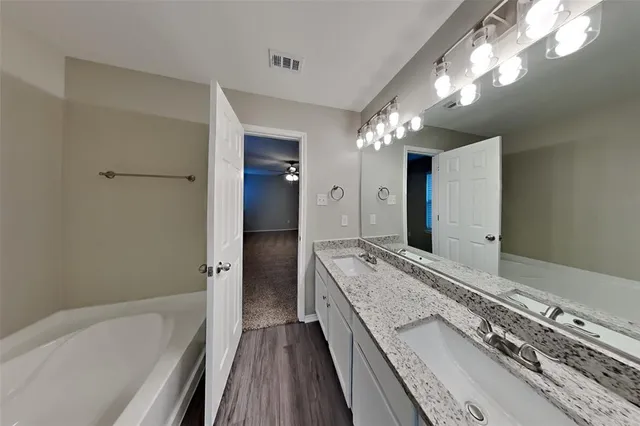 a spacious bathroom with a granite countertop sink a large mirror and shower