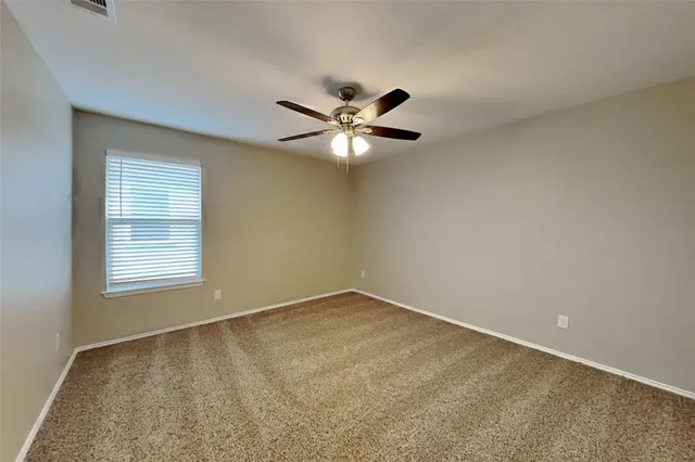 an empty room with a chandelier fan and windows