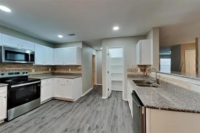 a kitchen with stainless steel appliances granite countertop a sink stove microwave and cabinets