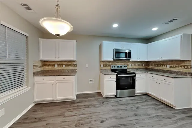 a kitchen with granite countertop white cabinets and stainless steel appliances