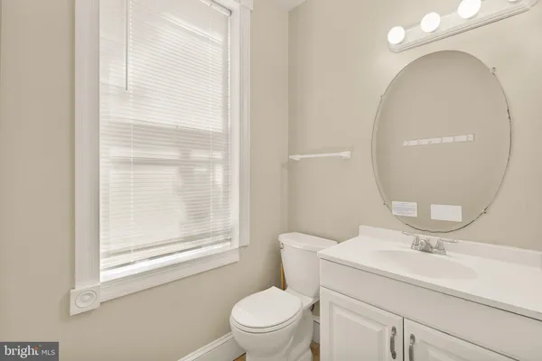 a bathroom with a toilet a sink a mirror and a window