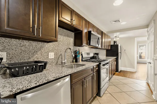 a kitchen with stainless steel appliances granite countertop a stove a sink and a microwave