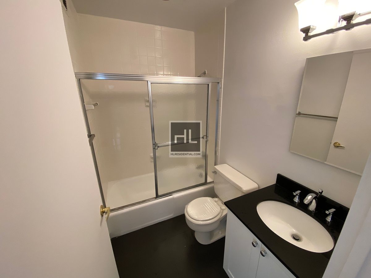 200 East 72nd Street, Unit 34N Manhattan, NY 10021 - Photo 12 of 12 a bathroom with a toilet sink vanity shower and mirror