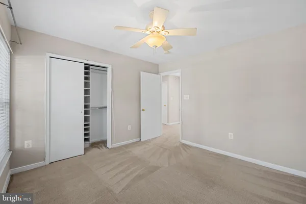 an empty room with closet and a ceiling fan