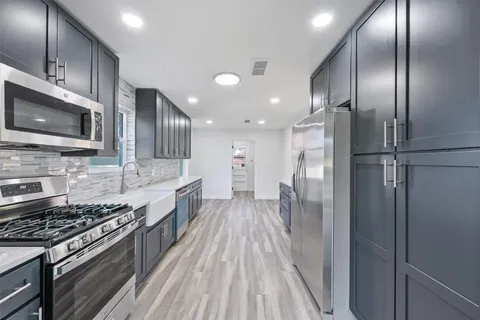 a large kitchen with stainless steel appliances granite countertop a stove a refrigerator and a microwave