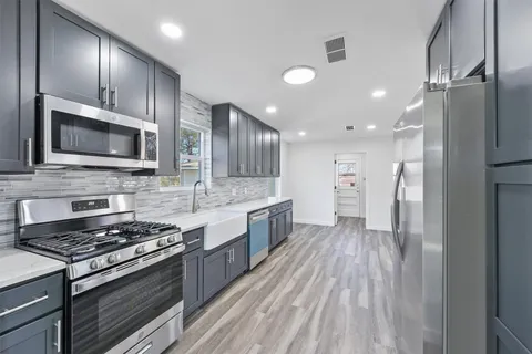 a kitchen with stainless steel appliances a stove a sink and a refrigerator