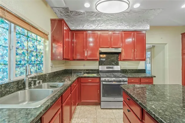 a kitchen with stainless steel appliances granite countertop a sink dishwasher a stove a refrigerator with a dining table and chairs