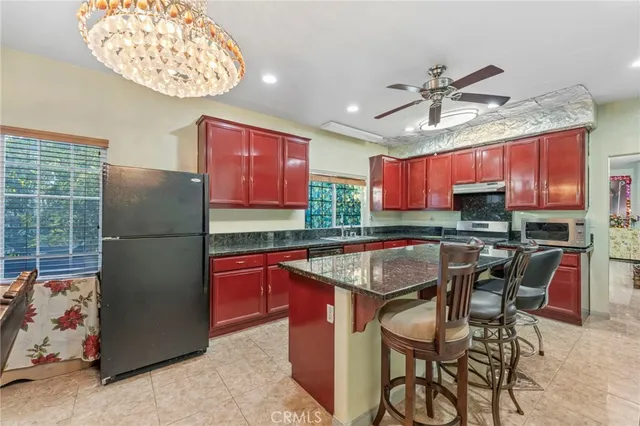 a kitchen with stainless steel appliances granite countertop a sink a stove a dining table and chairs with wooden floor