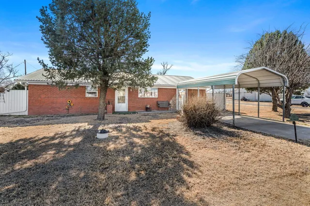 a backyard of a house with table and chairs under an umbrella