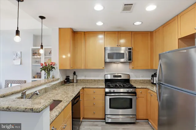 a kitchen with stainless steel appliances granite countertop a sink a stove and a refrigerator