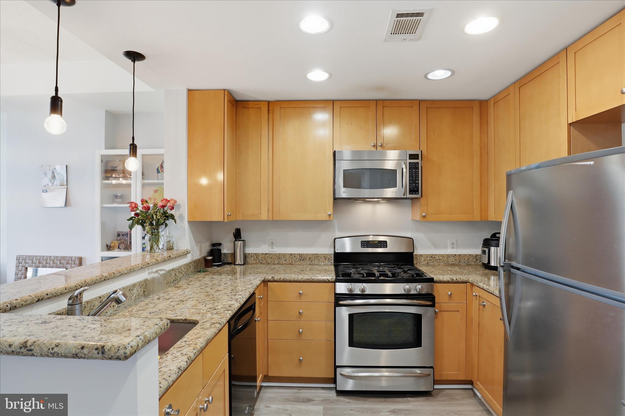 a kitchen with stainless steel appliances granite countertop a sink a stove and a refrigerator