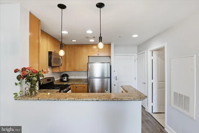 a kitchen with kitchen island a counter top space a sink stainless steel appliances and cabinets