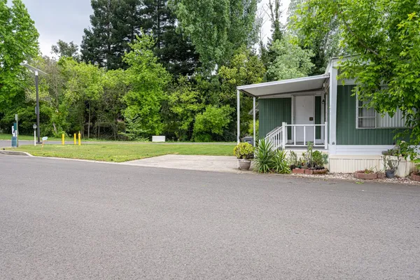 a view of a house with a yard and large trees