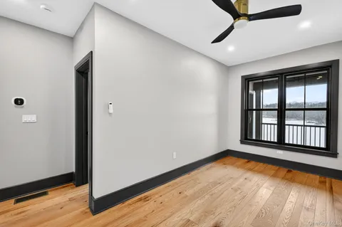 a view of empty room with wooden floor and fan