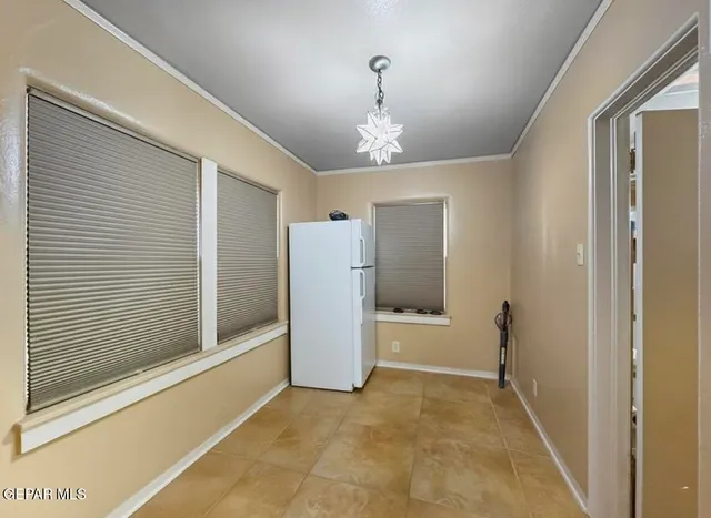 a view of a hallway with a refrigerator and chandelier