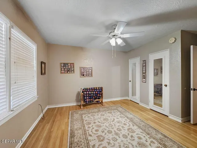 a view of a bedroom with wooden floor and a ceiling fan