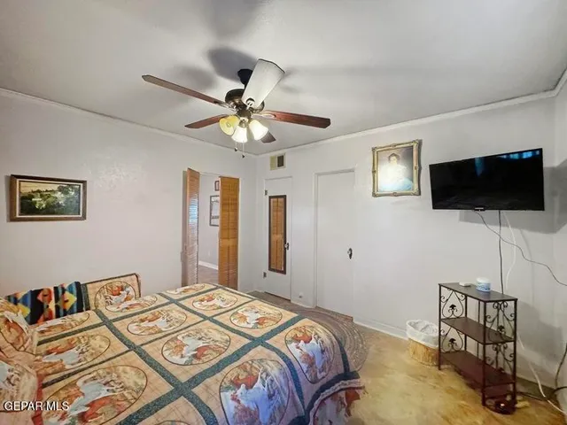 a bedroom with a bed a flat screen tv and a chandelier