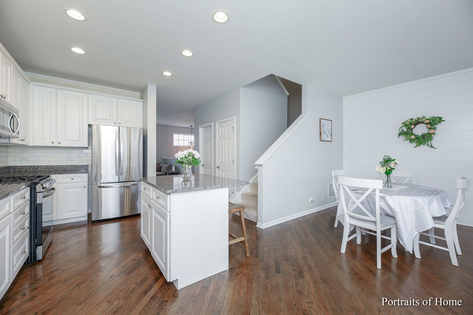 126 Jackson Street Gilberts, IL 60136 - Photo 9 of 25 a kitchen with stainless steel appliances a refrigerator a stove a dining table and chairs with wooden floor