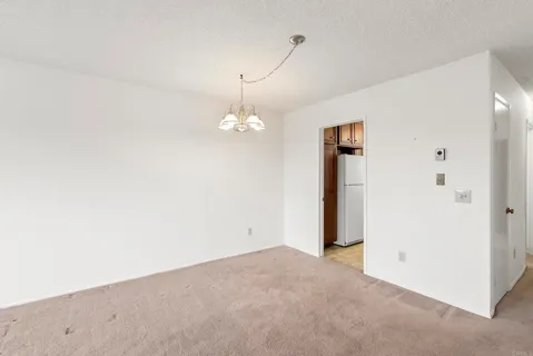 an empty room with a chandelier fan and windows
