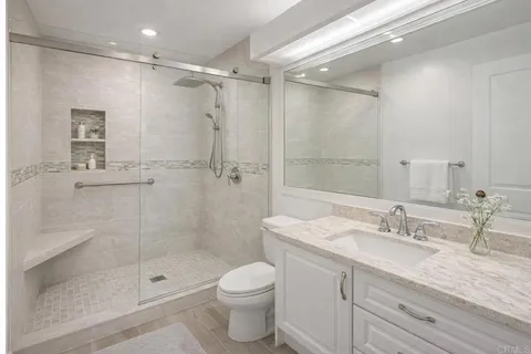 a bathroom with a granite countertop sink a toilet and shower