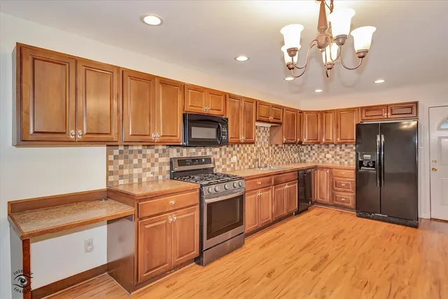 a kitchen with stainless steel appliances granite countertop a refrigerator a sink dishwasher a stove with wooden cabinets and floor