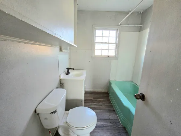 a white toilet sitting next to a bathroom sink and a window