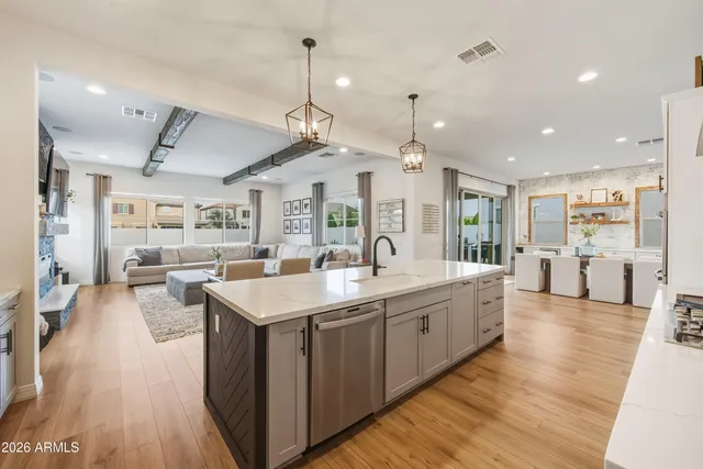 a large kitchen with kitchen island a stove a sink a center island and wooden floor