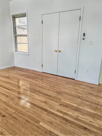 a view of an empty room with wooden floor and closet