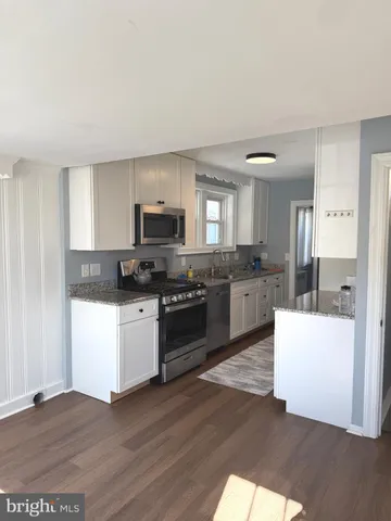 a kitchen with granite countertop white cabinets and stainless steel appliances