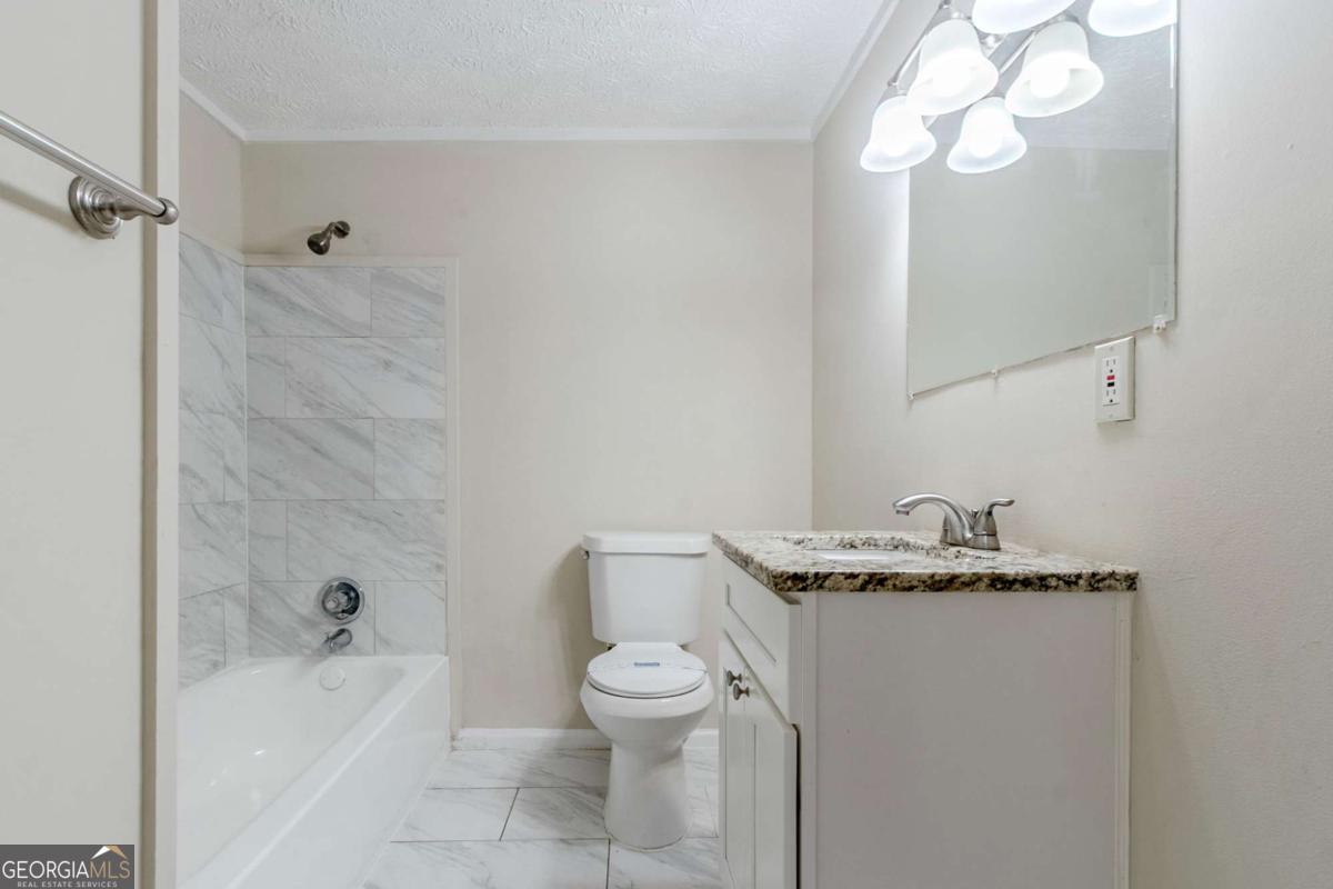 1715 Lee Street Decatur, GA 30035 - Photo 13 of 25 a bathroom with a granite countertop sink a toilet and shower