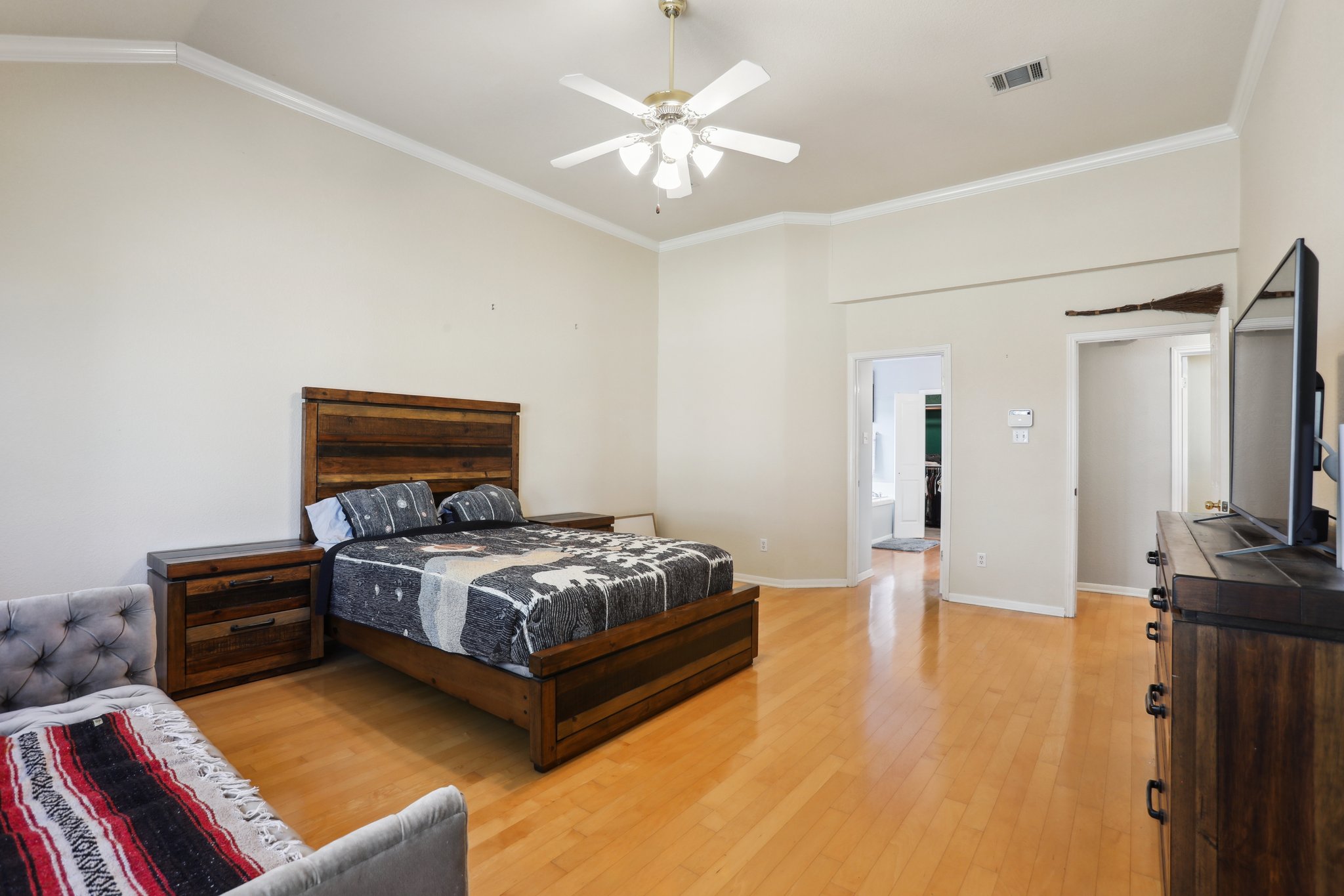 13541 Anarosa Loop Austin, TX 78727 - Photo 12 of 27 Spacious bedroom featuring vaulted ceilings, crown molding, wood-finish flooring, a ceiling fan, and multiple doorways