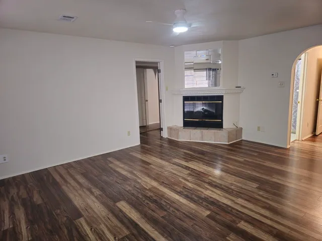 an empty room with wooden floor fireplace and windows