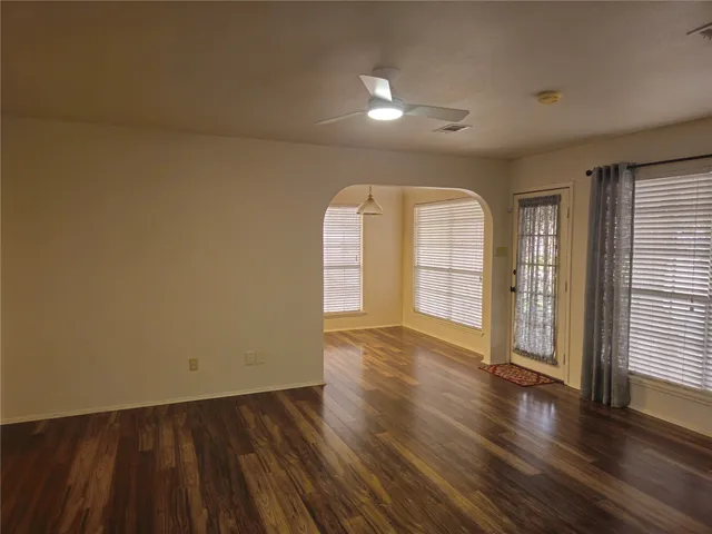 an empty room with wooden floor and windows