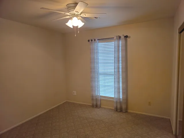 an empty room with windows and fan