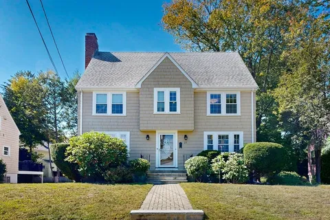 a front view of house with yard and trees in the background