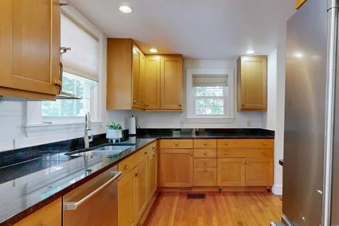 a kitchen with stainless steel appliances granite countertop wooden cabinets a sink and dishwasher a oven with wooden floors