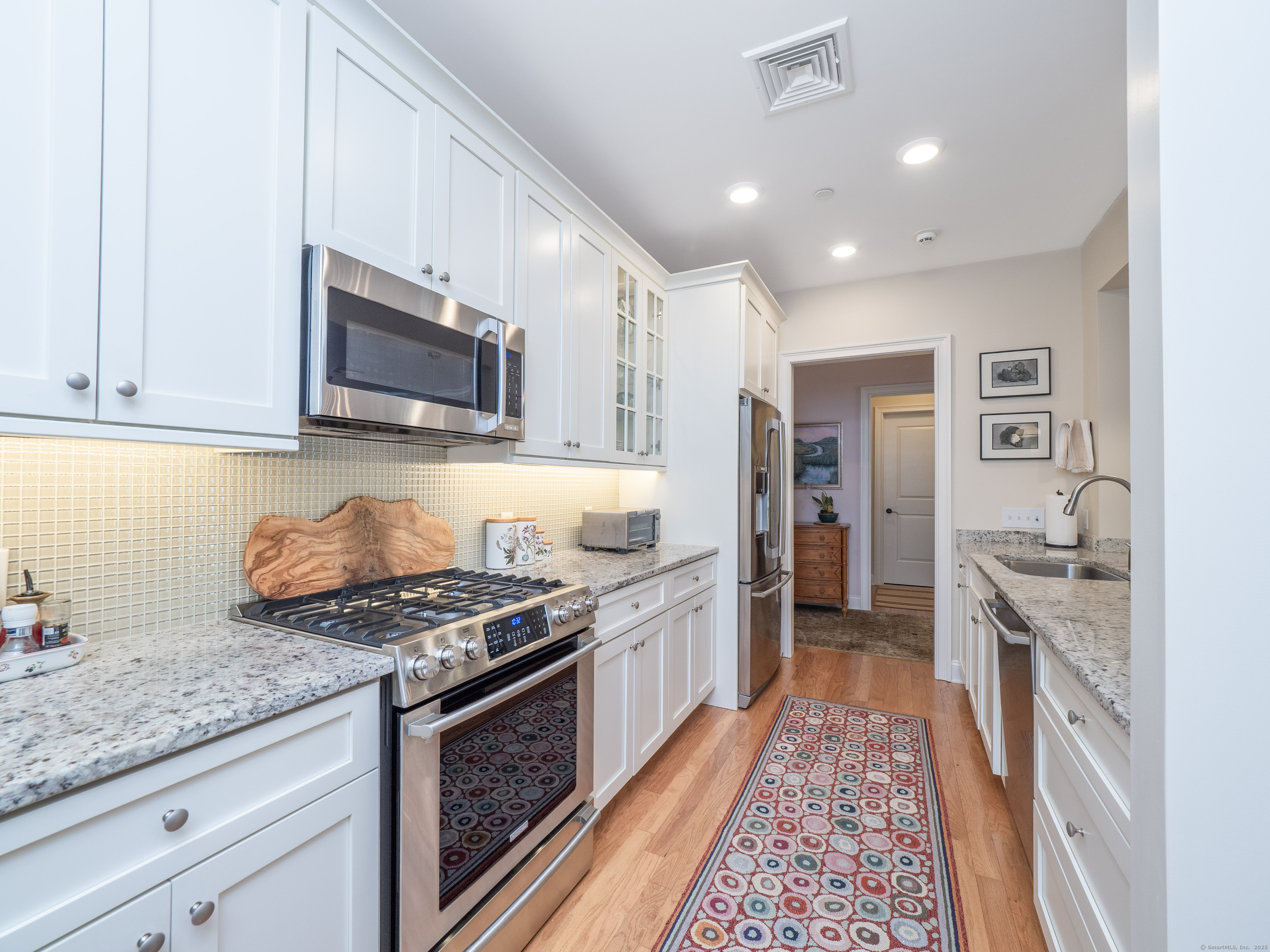 77 Sunset Lane, Unit 223 Ridgefield, CT 06877 - Photo 8 of 38 a kitchen with stainless steel appliances granite countertop a stove top oven a sink dishwasher and a microwave oven with cabinets